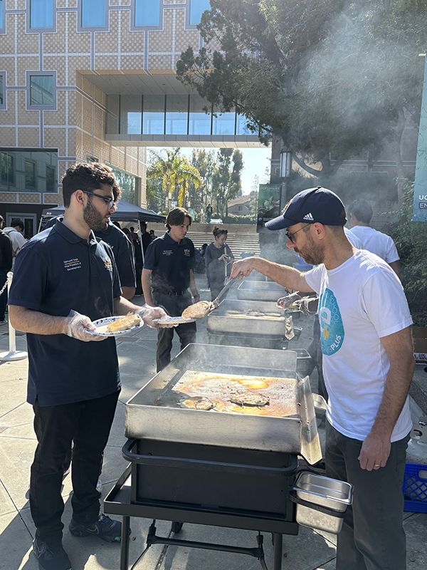 Totah assists Dean Magnus Egerstedt in preparing pancakes for the E-Week Dean’s Breakfast