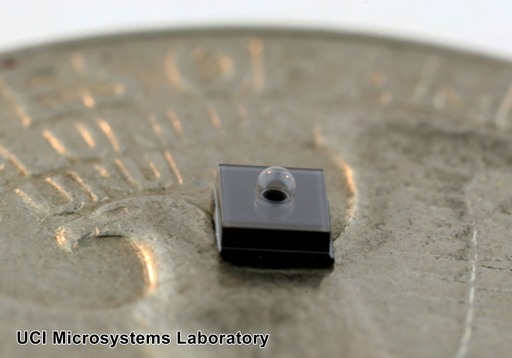 Diced silicon chip with a side length of 2mm on a U.S. quarter. The chip contains a blown glass sphere with a diameter of less than 1mm.