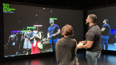 Ph.D. graduate Jad Al Aaraj (right) demonstrates technology he created that enables people to opt out of visual tracking by public cameras.
