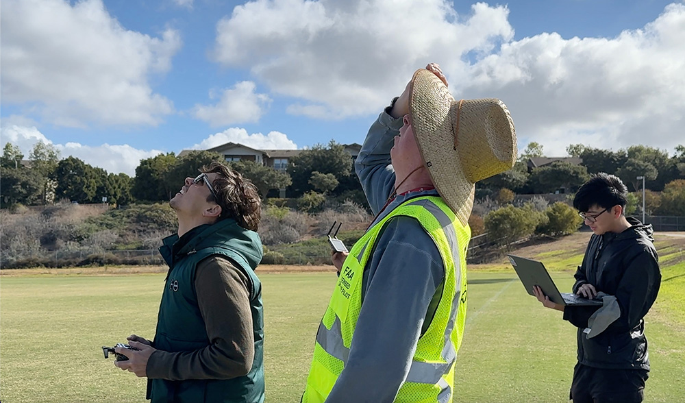 From left: Computer science engineering senior Aiden Dodge, Professor Peter Burke and teaching assistant Patrick Rwei watch Dodge’s drone fly.