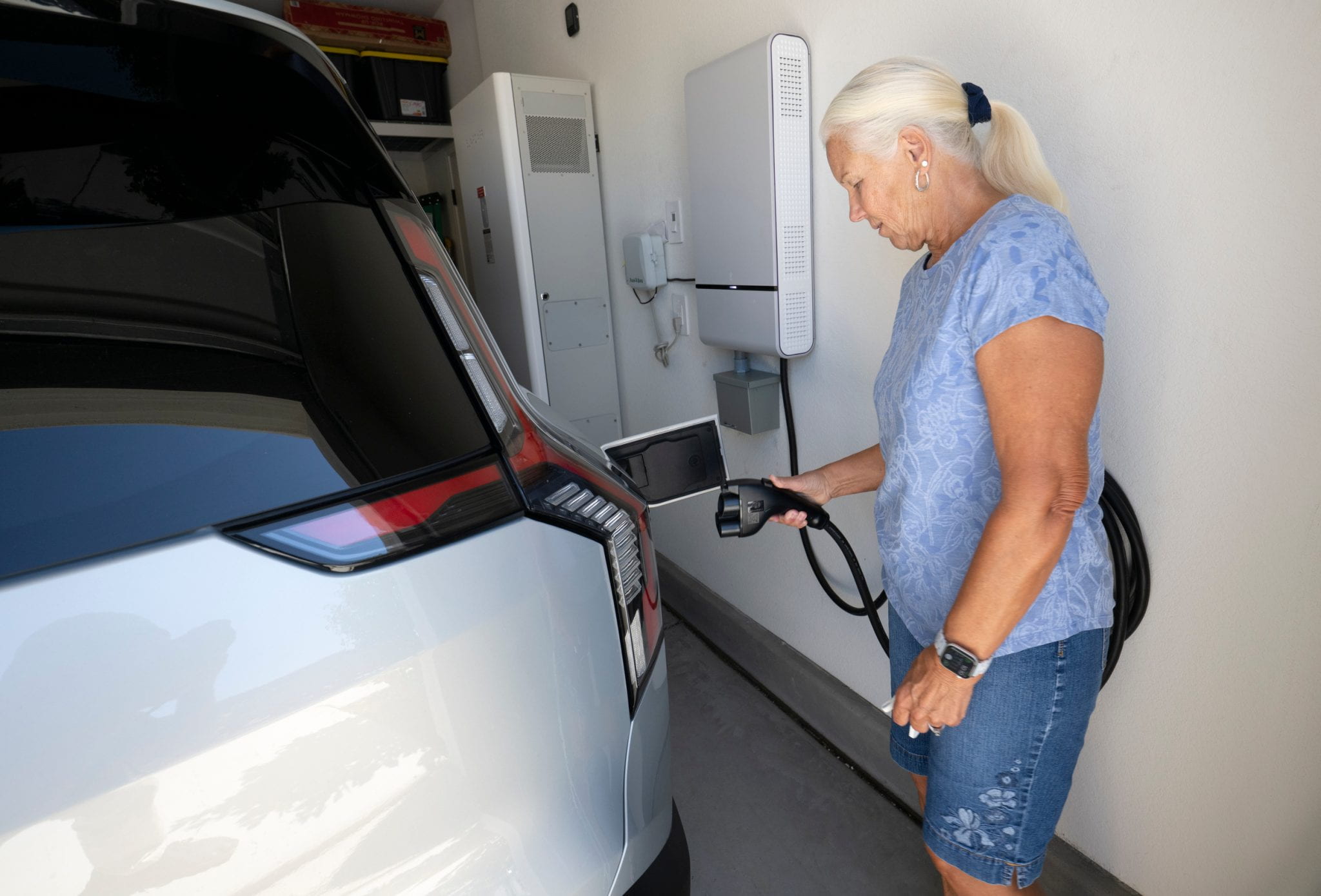 Woman plugs car into garage outlet.